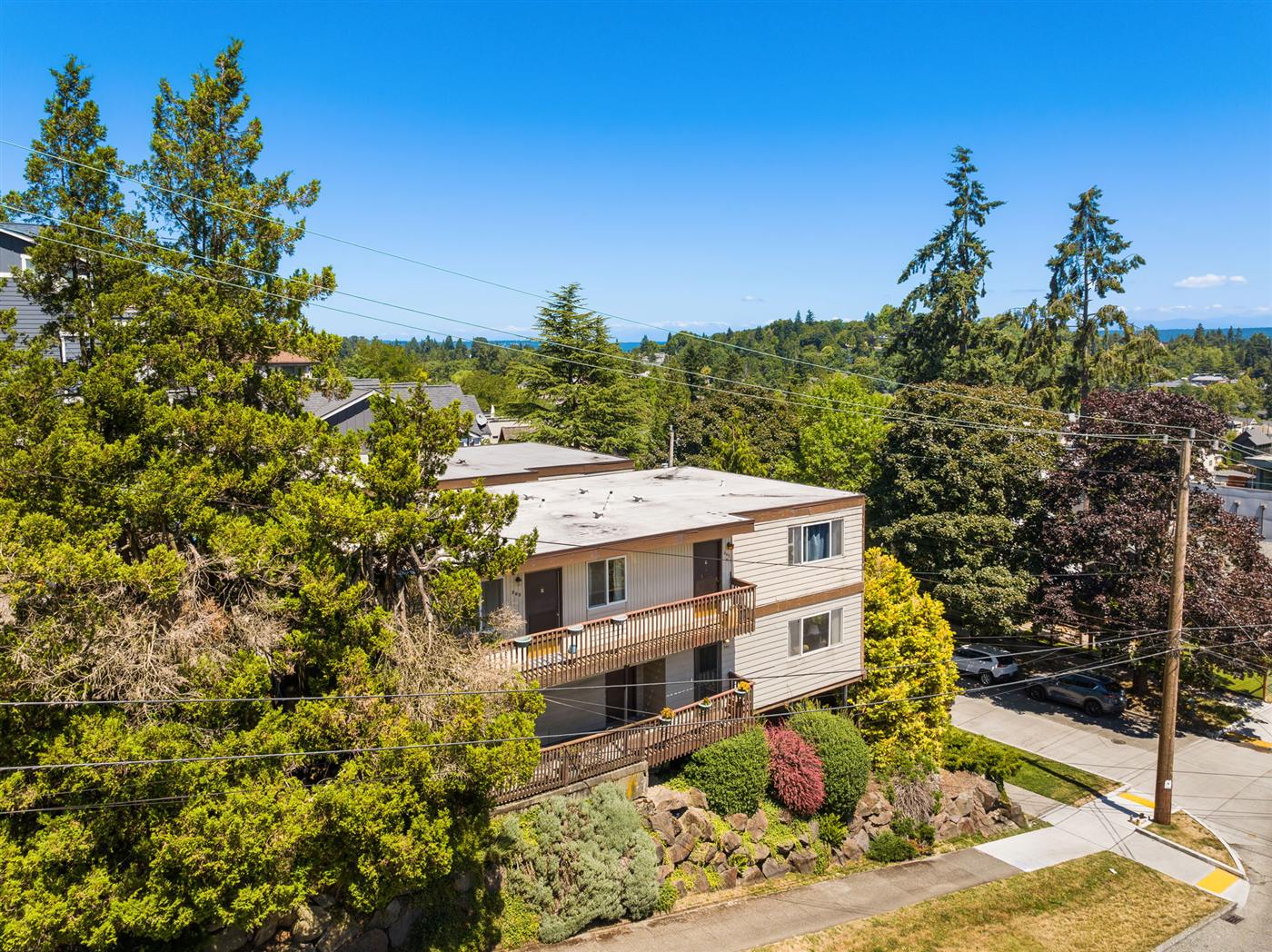 Elevated corner view of 201 and 205 26th Ave E, decks facing the street and Puget Sound on the horizon
